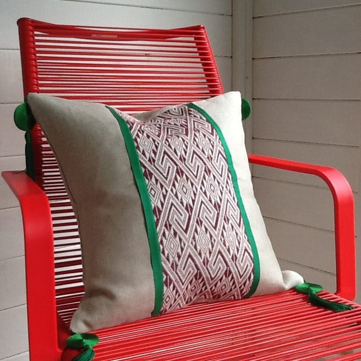 A modern, pillar box red, wire chair with a tasselled natural linen cushion in chocolate Thai textile with green silk trim.