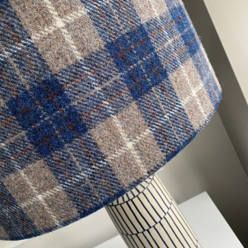 Detail of a tartan check drum shade in blues and warm grey.