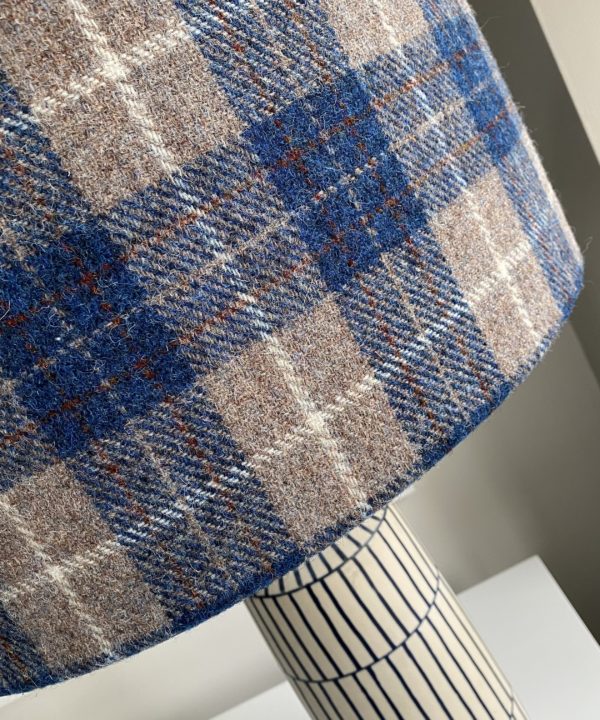 Detail of a tartan check drum shade in blues and warm grey.