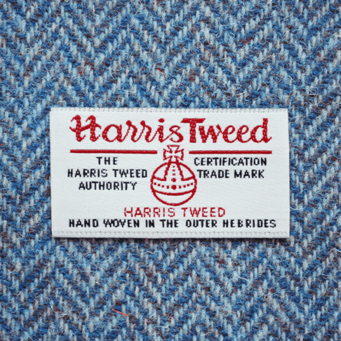 Close-up shot of Harris tweed orb label on blue herringbone tweed.