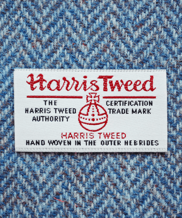 Close-up shot of Harris tweed orb label on blue herringbone tweed.