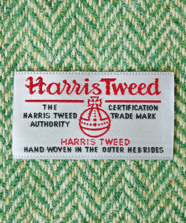 Close-up shot of Harris tweed orb label on green herringbone tweed.