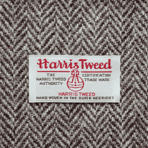 Close-up shot of Harris tweed orb label on grey herringbone tweed.