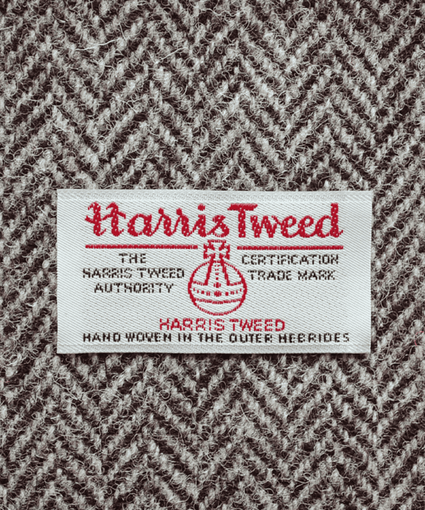 Close-up shot of Harris tweed orb label on grey herringbone tweed.