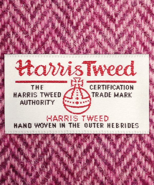 Close-up shot of Harris tweed orb label on pink herringbone tweed.