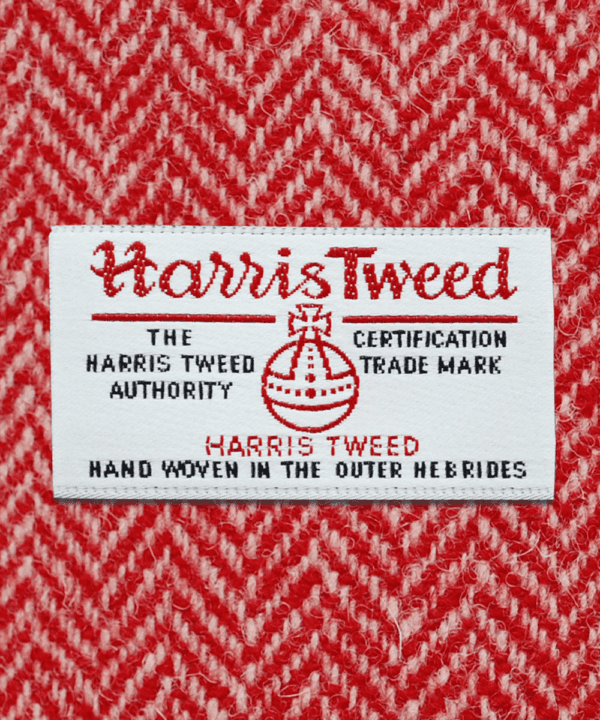 Close-up shot of Harris tweed orb label on red herringbone tweed.