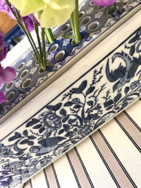 A detail of the Dutch Delft-pottery-inspired 'Flowerbrick' rectangular vase displayed on a striped tablecloth.