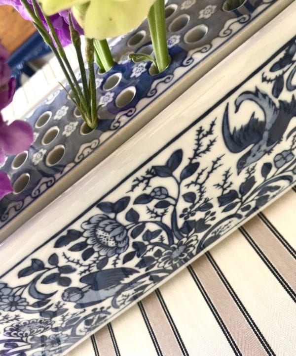 A detail of the Dutch Delft-pottery-inspired 'Flowerbrick' rectangular vase displayed on a striped tablecloth.