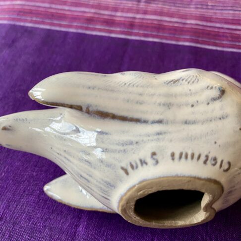 Reverse of bird sculpture with ceramicist's signature.