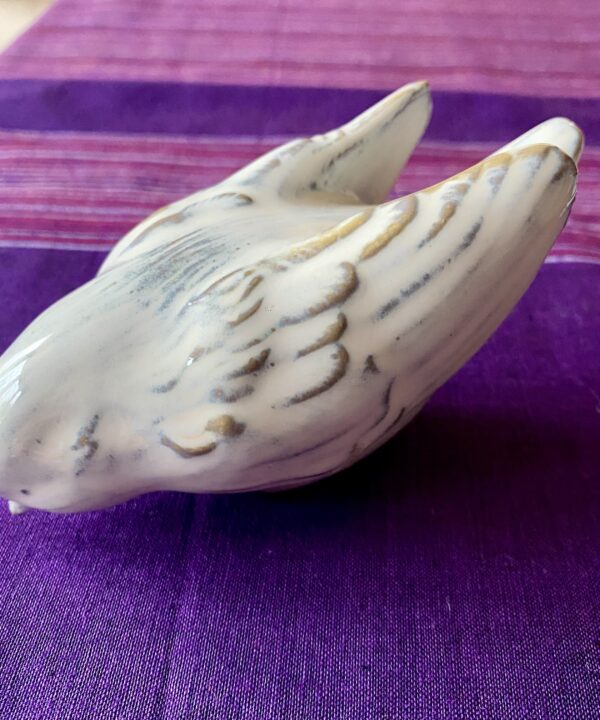 A white ceramic bird sculpture entitled 'Bird Down'.