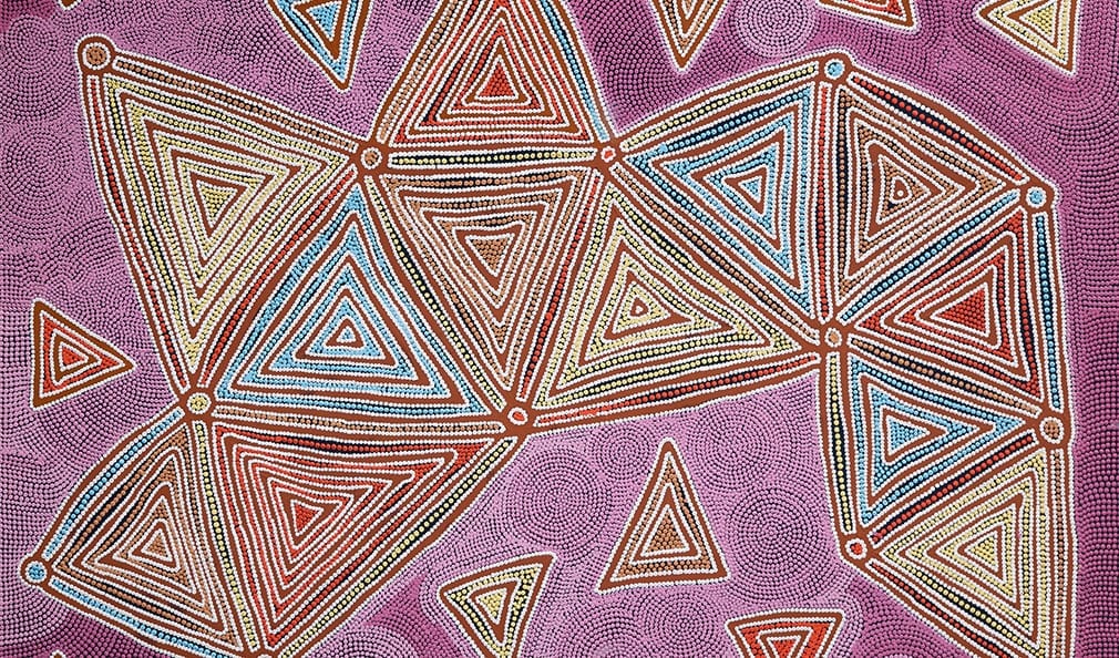 An almost geometric Aboriginal art canvas depicting triangular forms in pinks and blues.