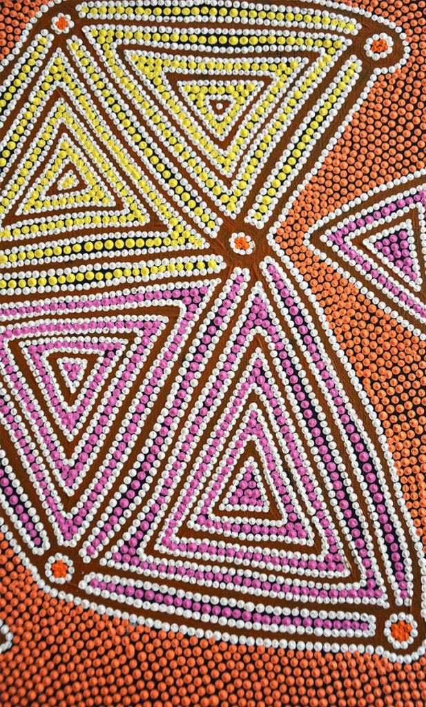 Close-up on an indigenous Australian Aboriginal artwork in a wonderful palette of orange, pink and yellow.