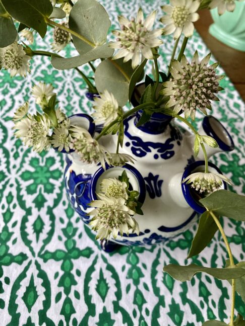 A blue and white small vase for the festive table in Dutch the tulipière style. Shown here on a green block print tablecloth filled with Astrantia.