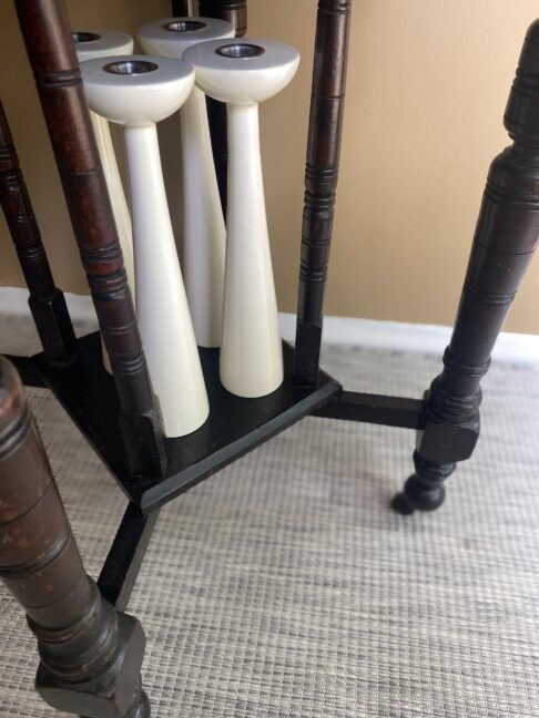 White gloss candlesticks stored under a dining room side table.