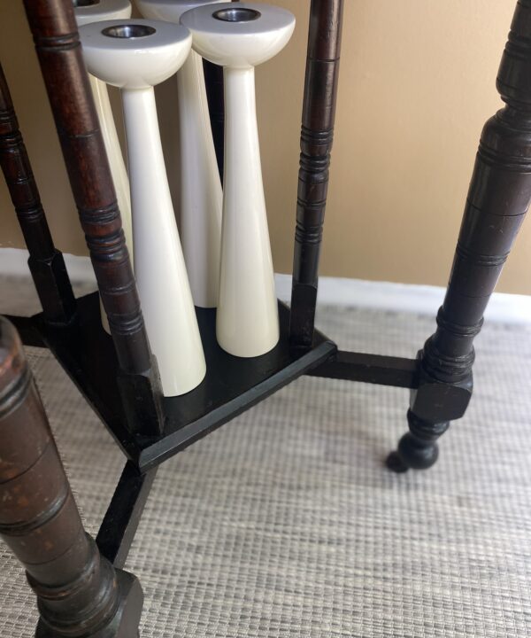 White gloss candlesticks stored under a dining room side table.