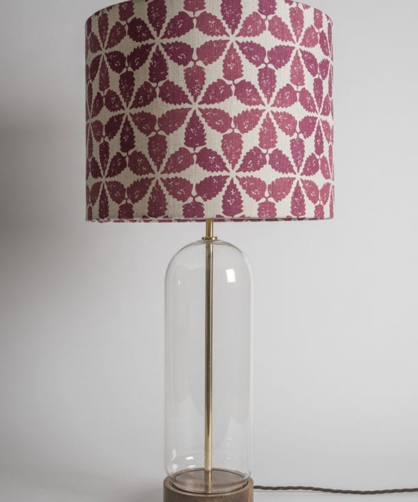 A clear glass lamp base with a Moroccan-print drum shade in red and cream.