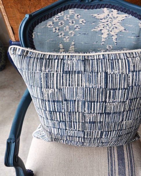 A hand-print, indigo linen cushion in a Japanese design on a carved, painted wooden French chair.