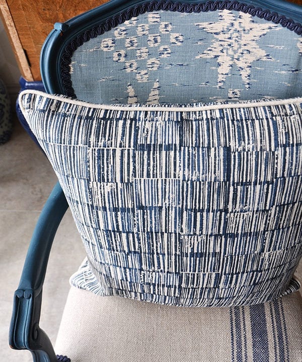 A hand-print, indigo linen cushion in a Japanese design on a carved, painted wooden French chair.