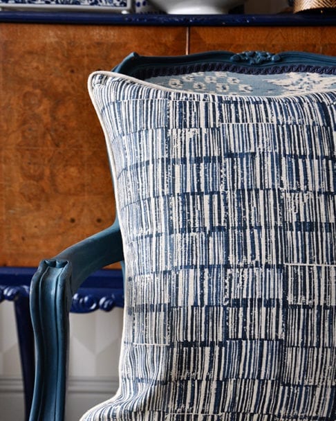 A hand-print, indigo linen cushion in a Japanese design on a carved, painted wooden chair.