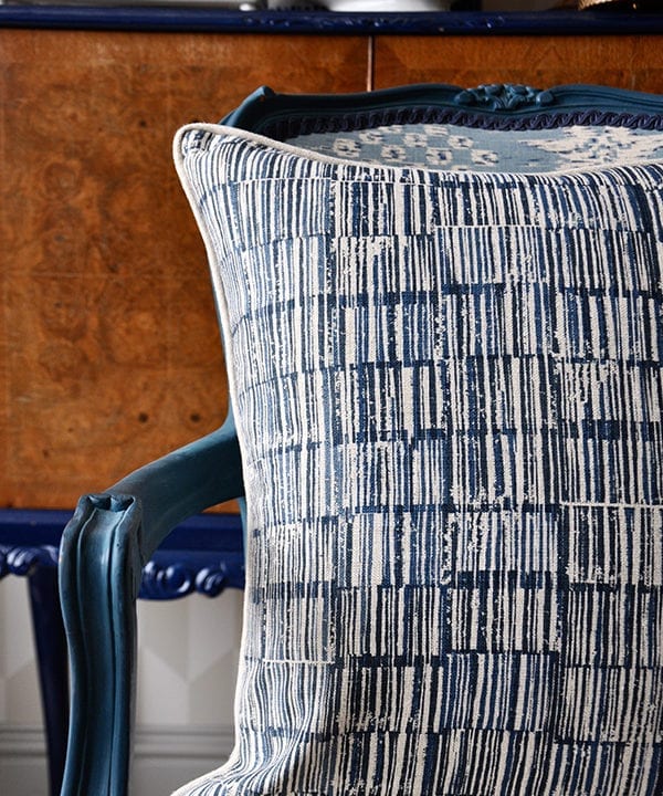 A hand-print, indigo linen cushion in a Japanese design on a carved, painted wooden chair.