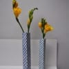 Hand-painted, lattice-patterned Japanese bud vases holding yellow freesias on a shelf.