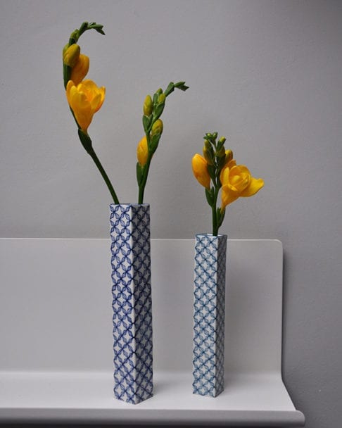 Hand-painted, lattice-patterned Japanese bud vases holding yellow freesias on a shelf.