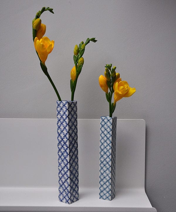 Hand-painted, lattice-patterned Japanese bud vases holding yellow freesias on a shelf.