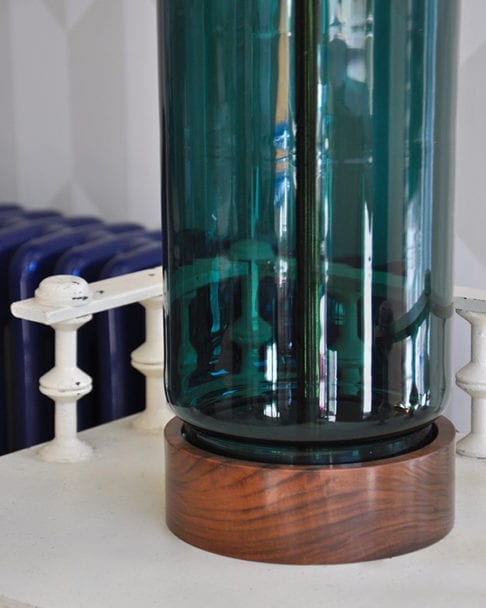 A hand-blown teal glass and wood lamp base.