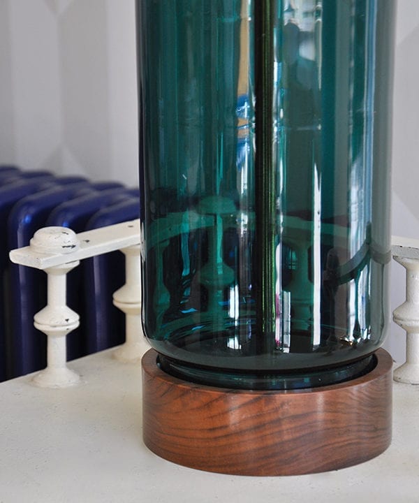 A hand-blown teal glass and wood lamp base.