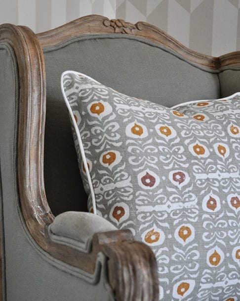 Detail of a celadon-colored, hand-print linen cushion on a French wooden chair.