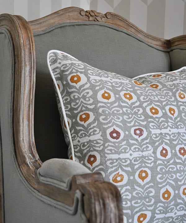 Detail of a celadon-colored, hand-print linen cushion on a French wooden chair.