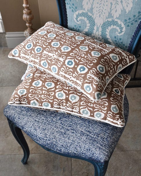 Brown, hand-print linen cushions on a blue chair in an Iznik design.