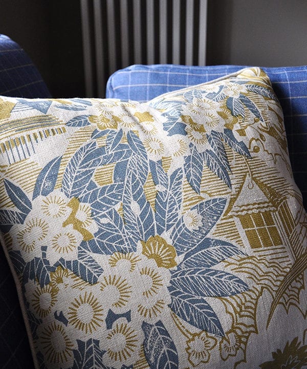 A close-up shot of Webb's Wonder hand-printed linen cushion in chartreuse on a blue check sofa available through Telescope Style.