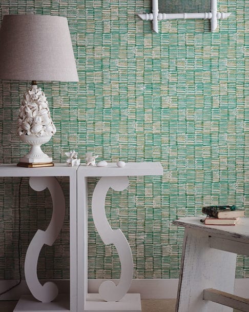 Japanese wallpaper in a verdant, green colourway styled with a white console and sculptural, ceramic lamp.