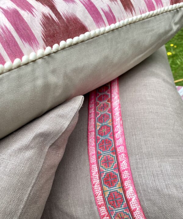 Detail of pink Ikat and vintage embroidery trimmed cushions.