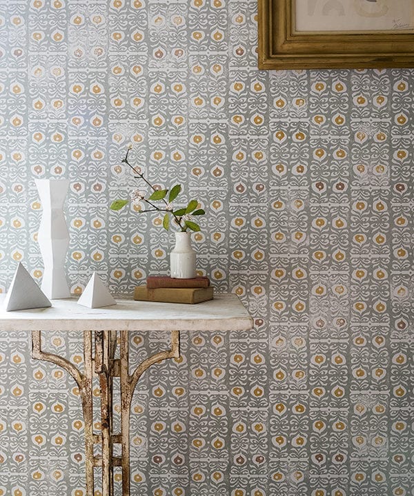 Iznik wallpaper in a celadon colour way is shown in a hallway setting with a stone and gold metal console table.