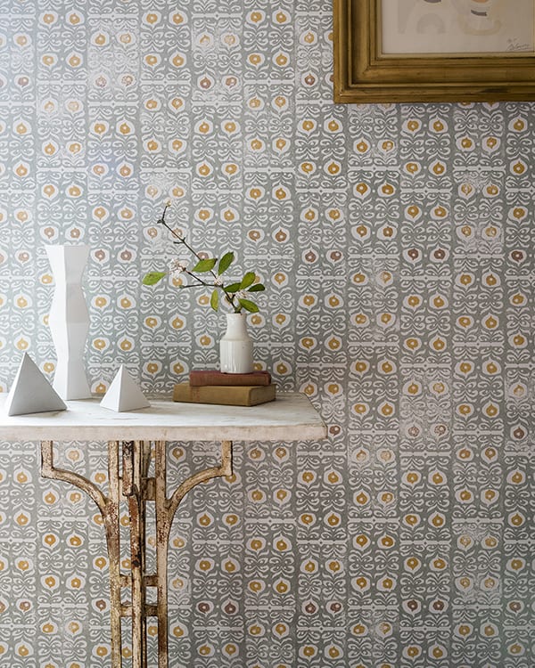 Iznik wallpaper in a celadon colour way is shown in a hallway setting with a stone and gold metal console table.