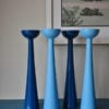 Tall coloured candlesticks in glossy blue hues sat on a teal painted sideboard.