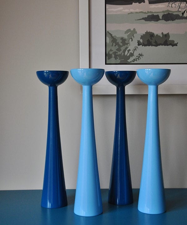 Tall coloured candlesticks in glossy blue hues sat on a teal painted sideboard.