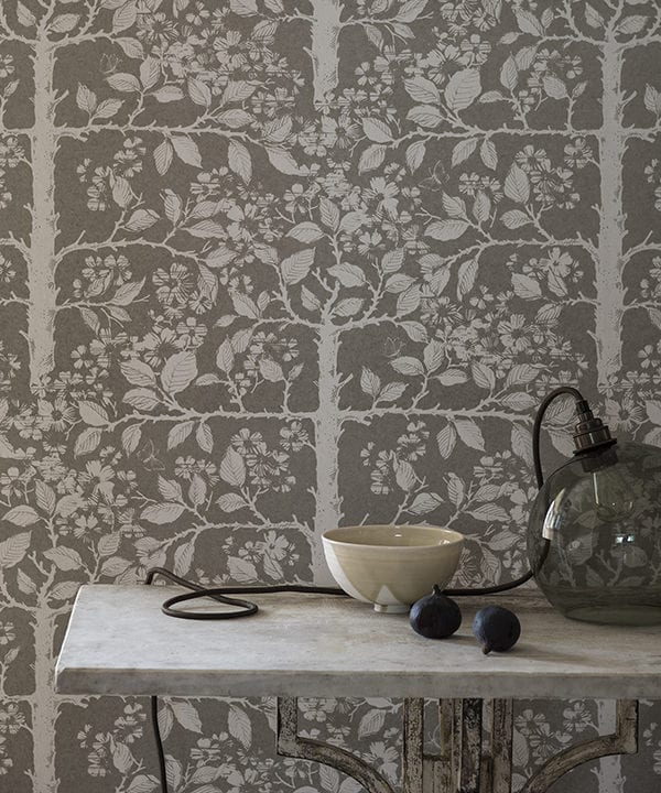 Grey botanical wallpaper in a chic neutral hue depicts espaliered trees redolent of walled gardens in English country houses.