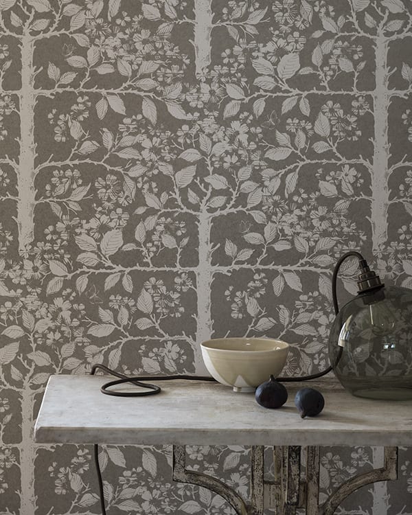 Grey botanical wallpaper in a chic neutral hue depicts espaliered trees redolent of walled gardens in English country houses.