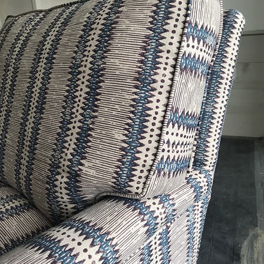 A comfortable armchair upholstered in blue and aubergine zig-zag stripe hand-print linen from Rapture & Wright.