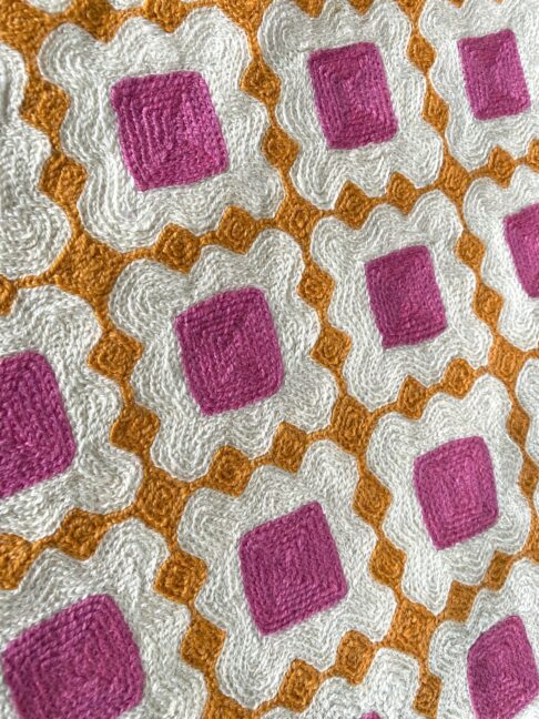 Kashmiri crewelwork detailing on a colourful pink and orange cushion.