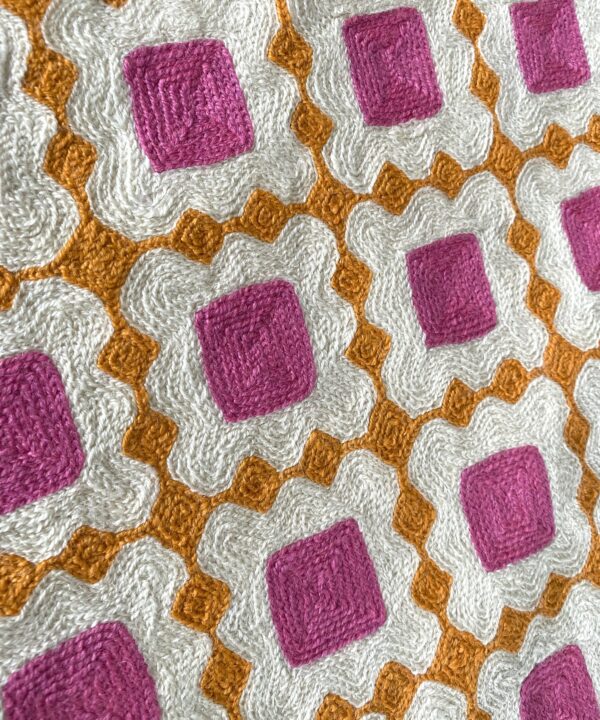 Kashmiri crewelwork detailing on a colourful pink and orange cushion.