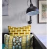 Crewel work cushion covers in turquoise and chocolate with a yellow geometric background, from Telescope Style.