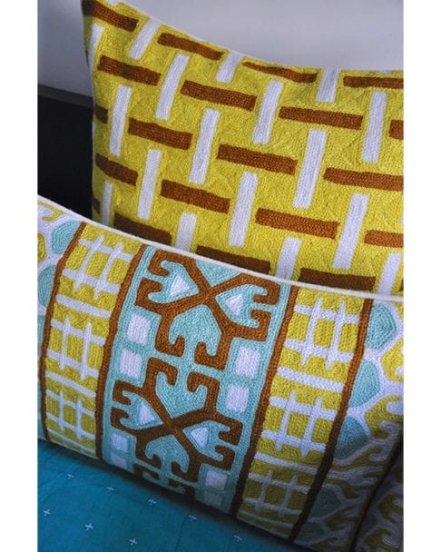 Detail of the Kashmiri crewelwork cushions in turquoise and chocolate with yellow geometric background from Telescope Style.