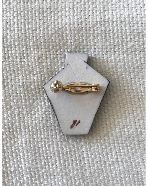 The reverse of the Japanese floral brooch showing the gold-coloured pin and artist's signature.