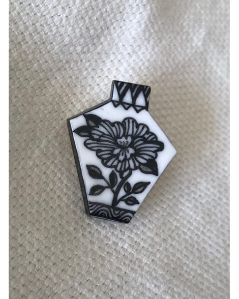 Japanese floral art hand-painted black and white brooch displayed on cream linen.