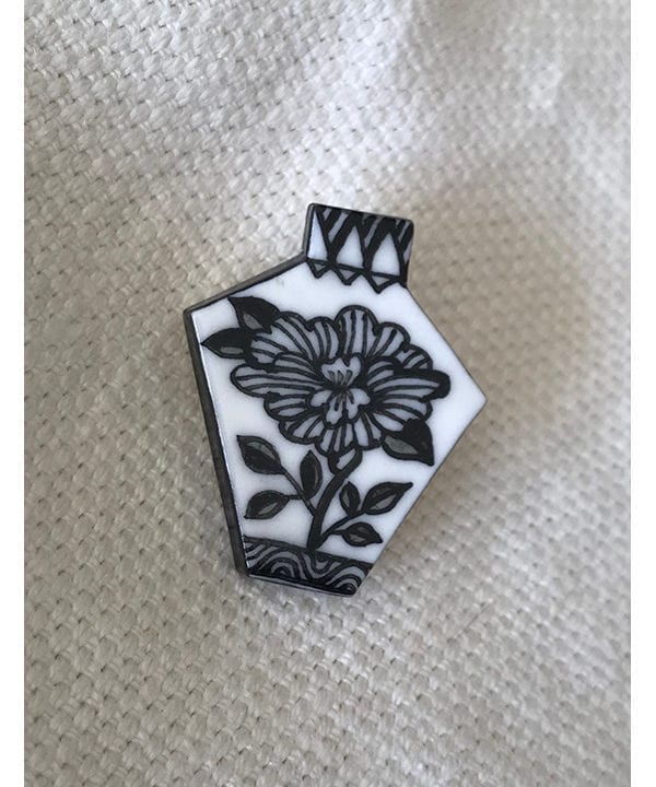 Japanese floral art hand-painted black and white brooch displayed on cream linen.