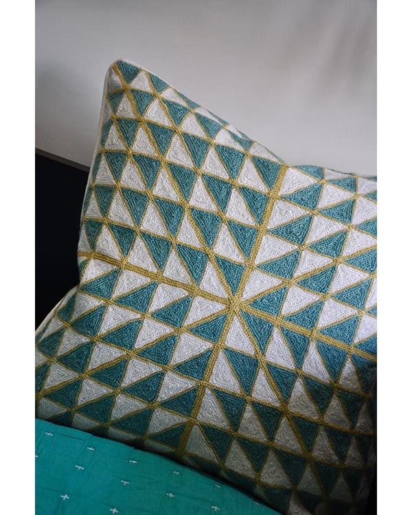 Teal crewelwork cushions with lime and geometric pattern.